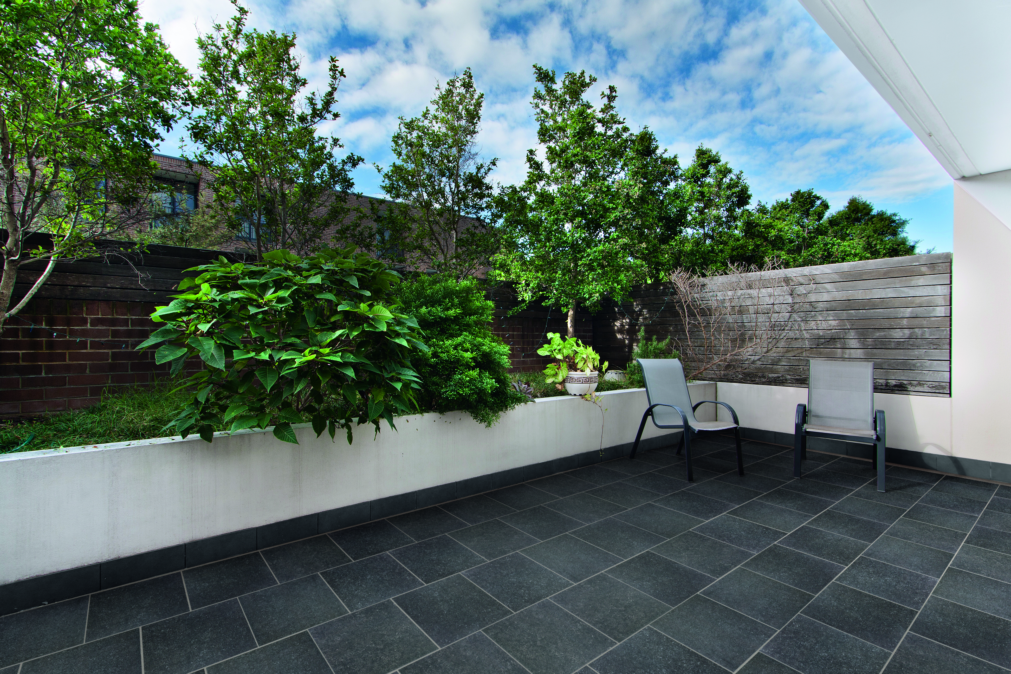 SYMPHONY® Plus Classic in Stone Black A black-tiled patio with two garden chairs