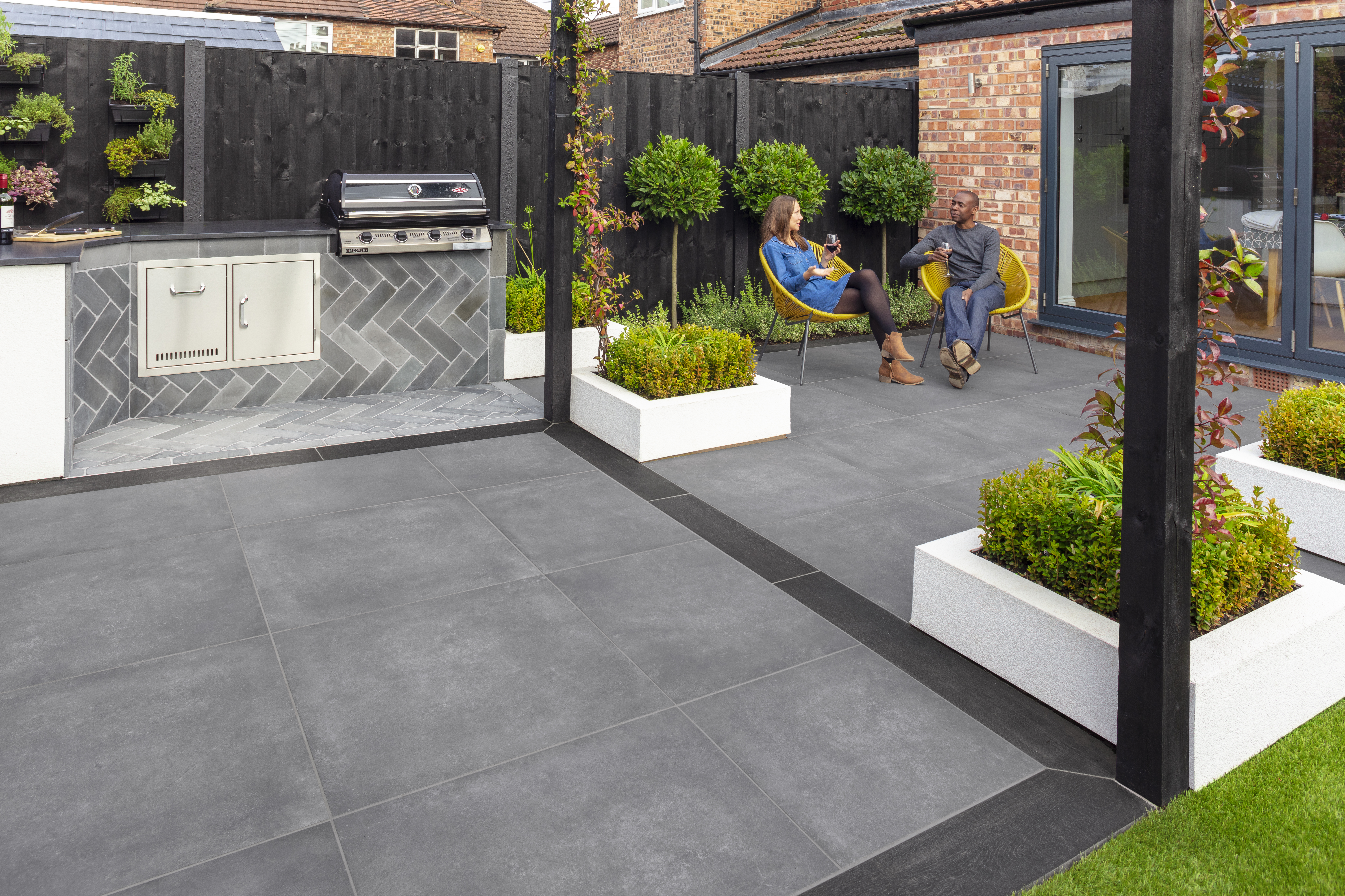 SYMPHONY® Urban in Steel Two people drinking wine on a large, grey patio with a barbecue