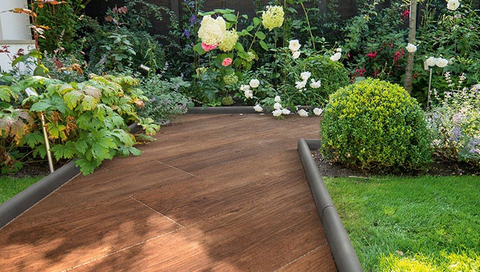 SYMPHONY® Plank in Cherry A wooden garden path with plants on either side