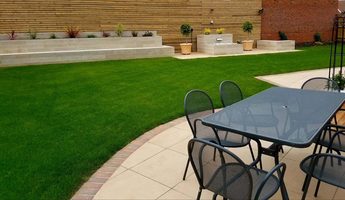 SYMPHONY® Classic in Buff A garden table on a round patio in front of a lawn